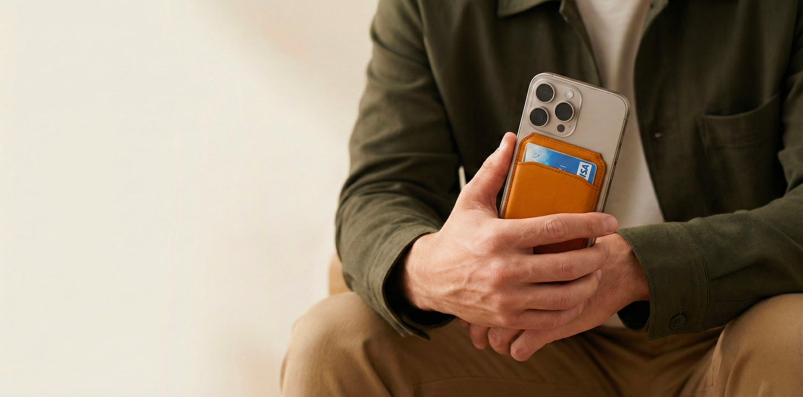 Person holding a phone with an orange case against a neutral background